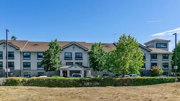 Ein Stay America Hotel mit zentralem Eingang, mehreren Etagen und einem Parkplatz.