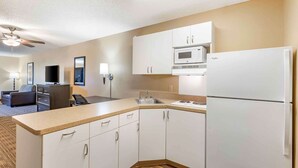 A compact kitchen with white cabinets, a microwave, and a refrigerator. There is a small sink and a countertop. - Extended Stay America Suites Great Falls Missouri River (Great Falls)