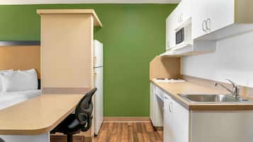 Una kitchenette compacta con microondas, pileta y alacenas.