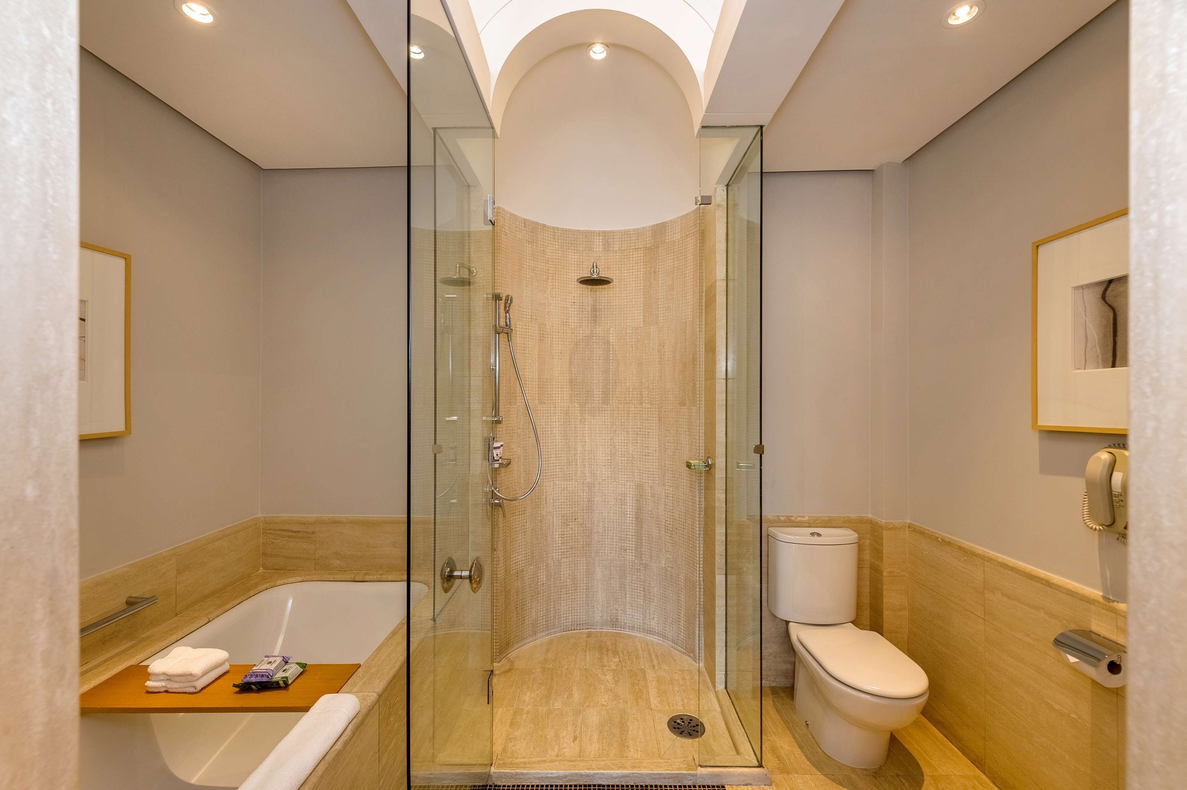 A modern bathroom with a glass-enclosed shower, a bathtub, and a toilet.