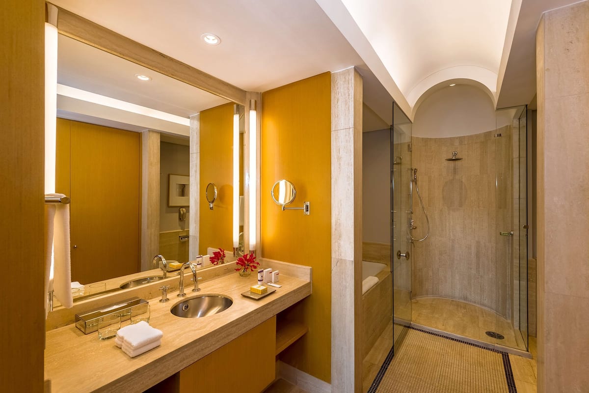 Un baño moderno con un espejo grande, lavamanos dobles y cabina de ducha con vidrio.