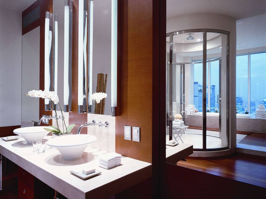 A modern bathroom with two sinks, a large mirror, and a glass-enclosed shower area.