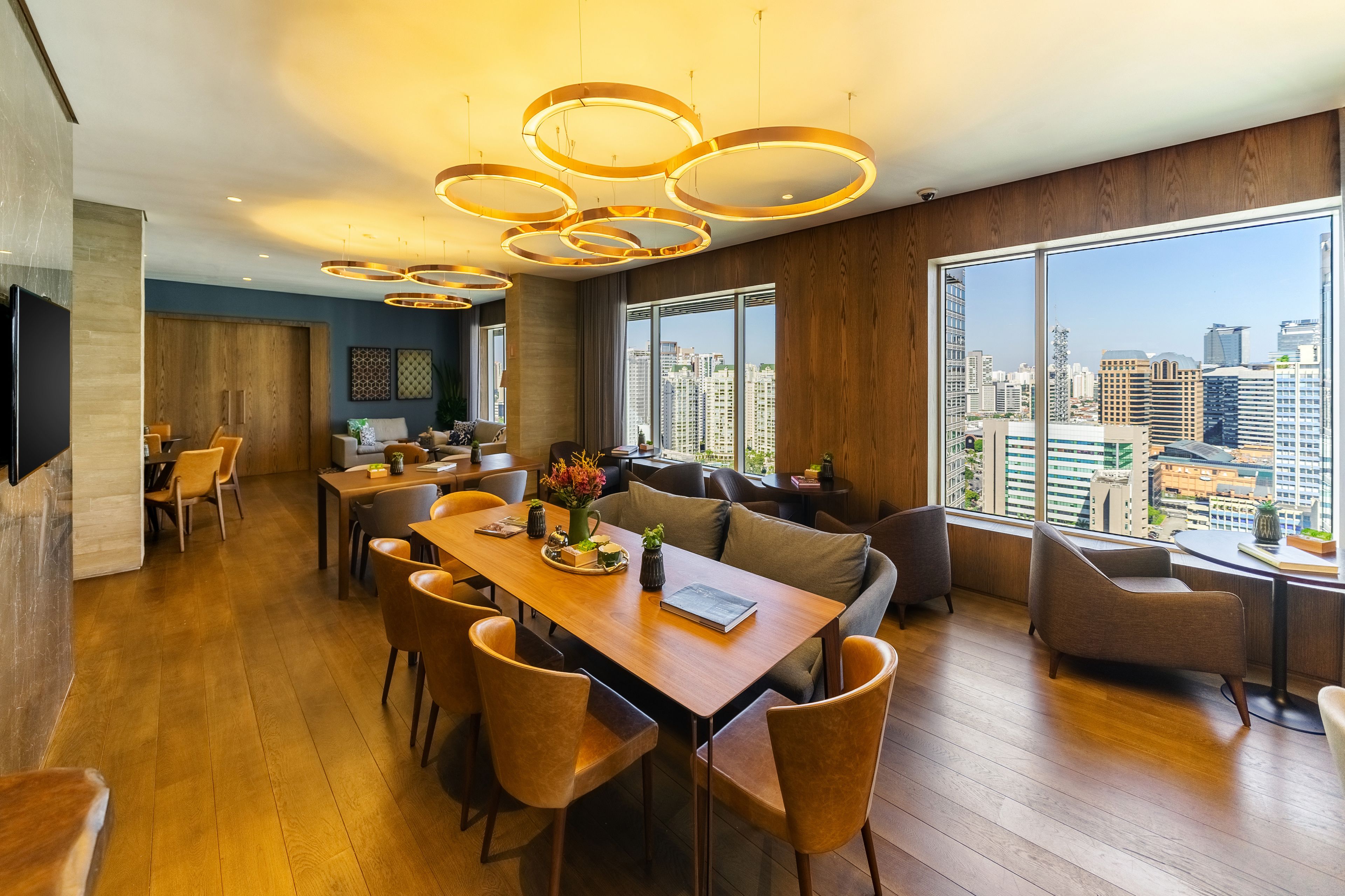 Un comedor moderno con una mesa y sillas de madera, un sofá y un amplio ventanal con vistas a la ciudad.