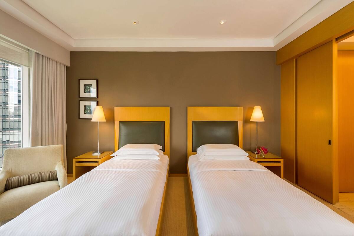 Habitación de hotel con dos camas, un sofá y una ventana con cortinas.