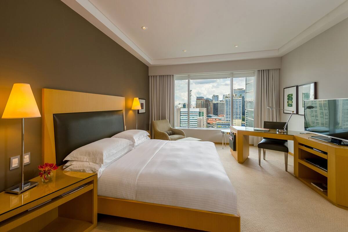Habitación de hotel con una cama grande, un escritorio, una silla y un televisor.