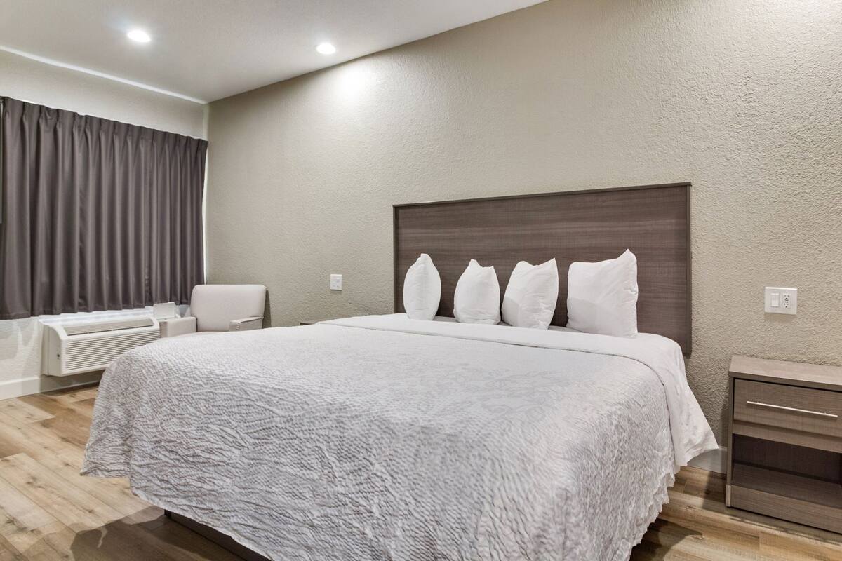 Una habitación de hotel moderna con una cama grande, una mesita de noche, una silla y un calefactor integrado.