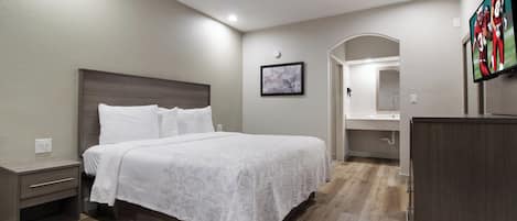 A hotel room with a bed, nightstands, a dresser, a mirror, and a TV.