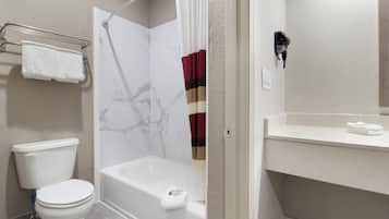 A bathroom with a toilet, a bathtub, and a shower curtain.