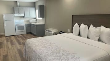 A hotel room with a bed, a kitchenette, and a bathroom.