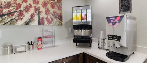 A coffee station with a Nescafé machine, a water dispenser, and a juice dispenser.