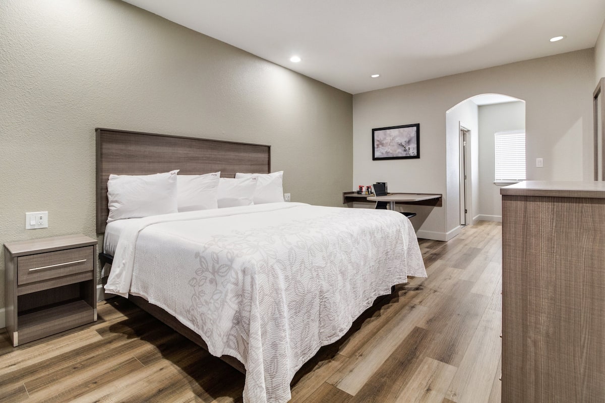 Un dormitorio moderno con una cama grande, una mesita de noche, un tocador y un cuadro en la pared.