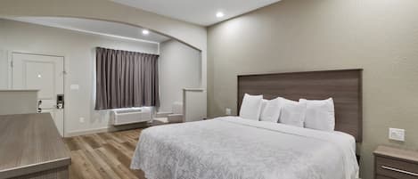 A hotel room with a large bed, a desk, a chair, and a window with curtains.
