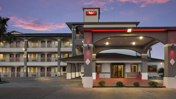 A hotel with a covered entrance, multiple balconies, and a sign indicating it is a Rydex hotel. - Red Roof Inn PLUS+ Galveston - Beachfront (Galveston)
