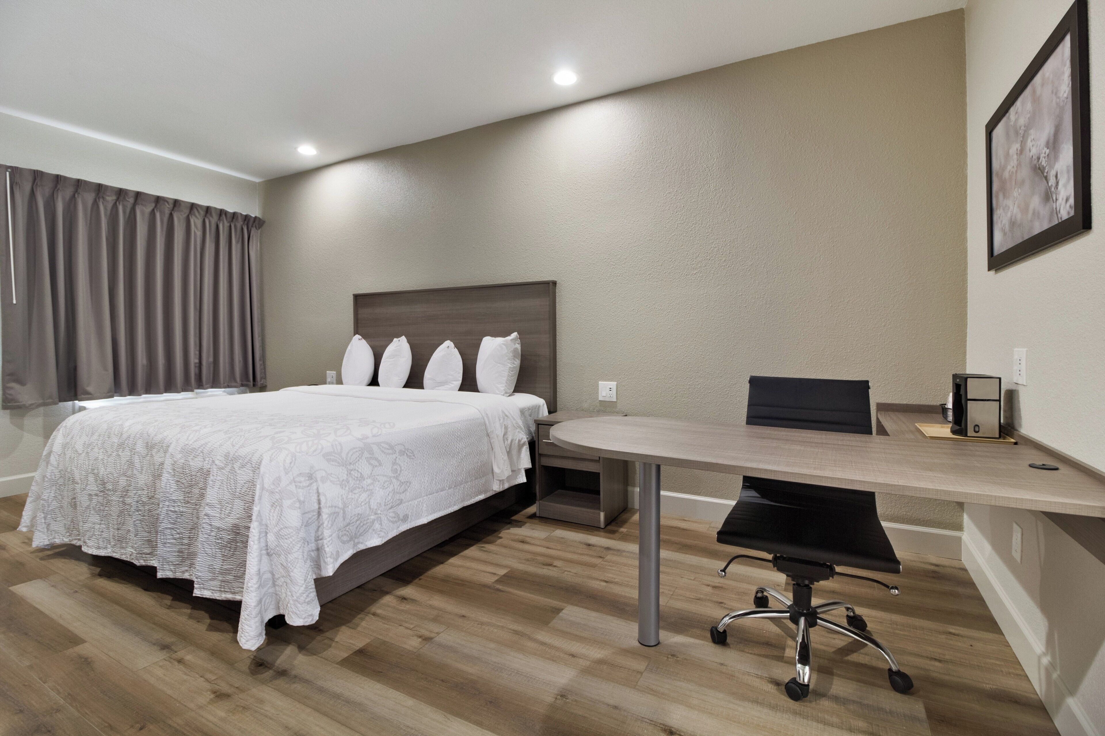 A hotel room with a bed, a desk, and a chair.
