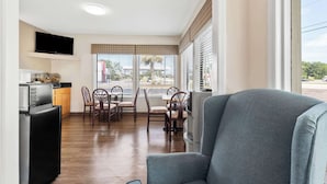 A compact living space with a dining area, kitchenette, and a large window with blinds. - Econo Lodge St. George (St. George)
