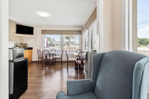 A compact living space with a dining area, kitchenette, and a large window with blinds.