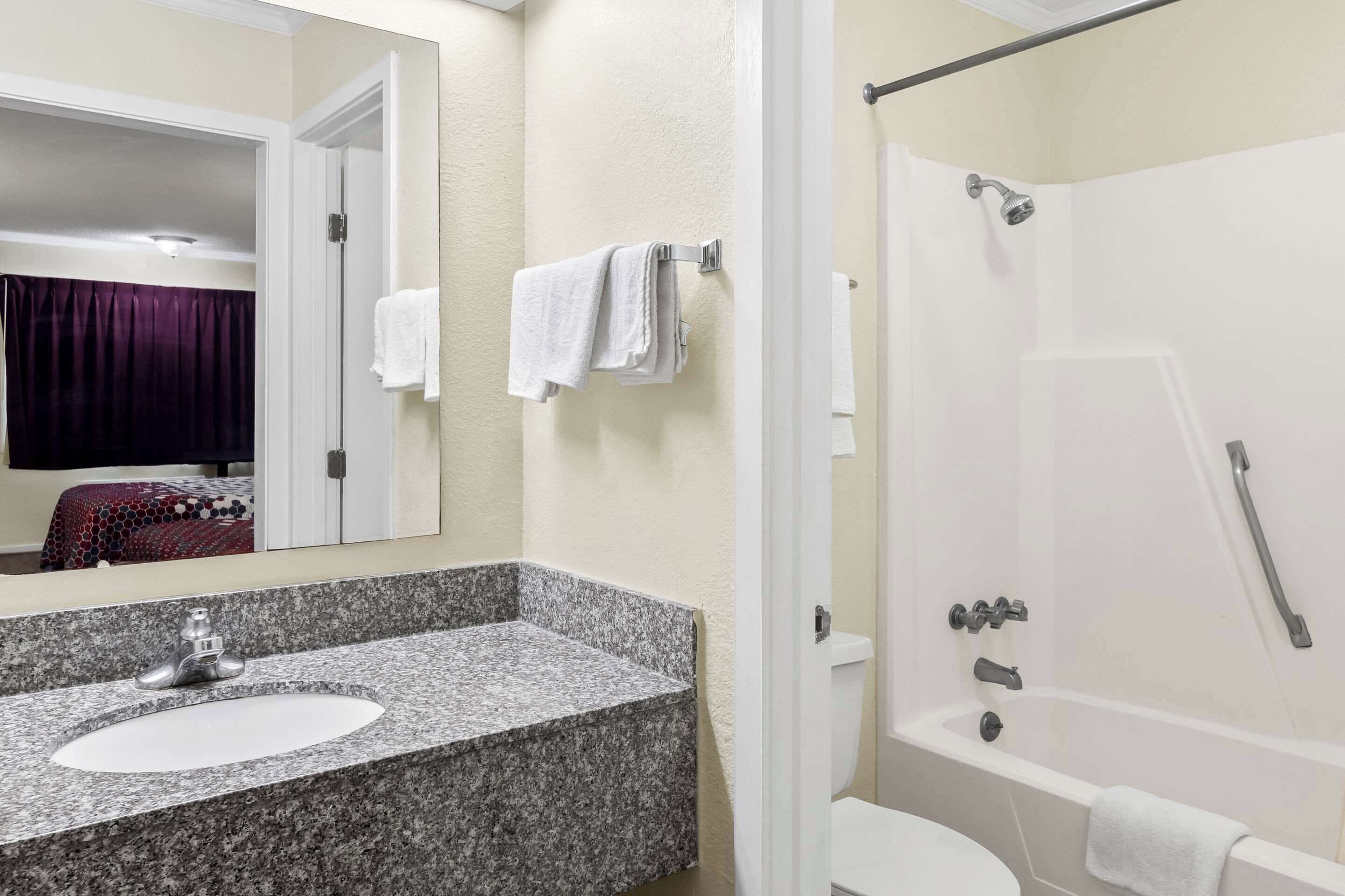 A bathroom with a granite sink, white toilet, and a walk-in shower.