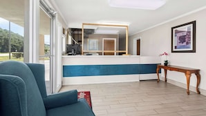 A hotel room with a large window, a blue sofa, a wooden table, and a blue and white accent wall. - Econo Lodge St. George (St. George)