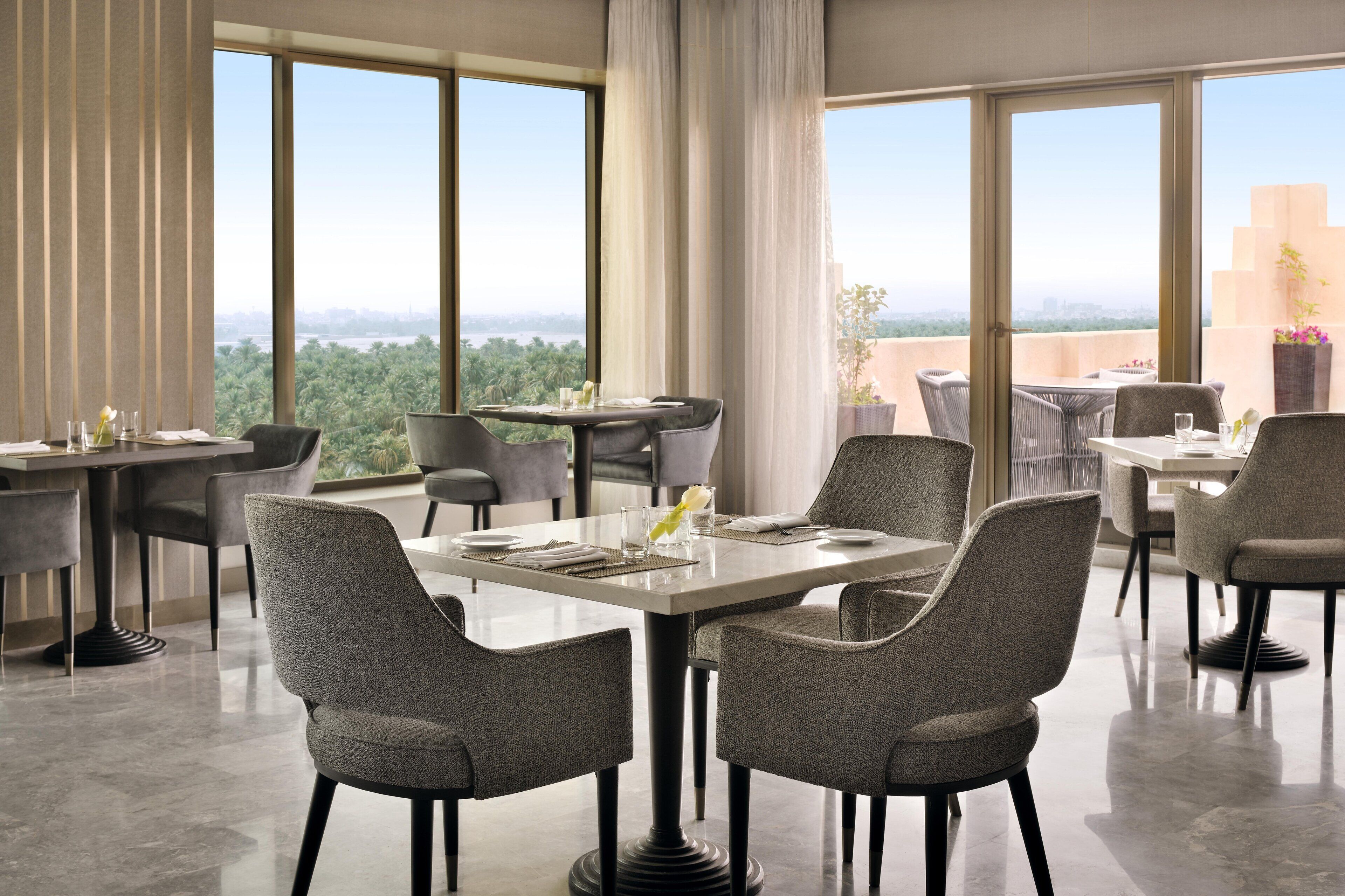 Un comedor moderno con amplios ventanales, vistas al verdor y un techo alto.