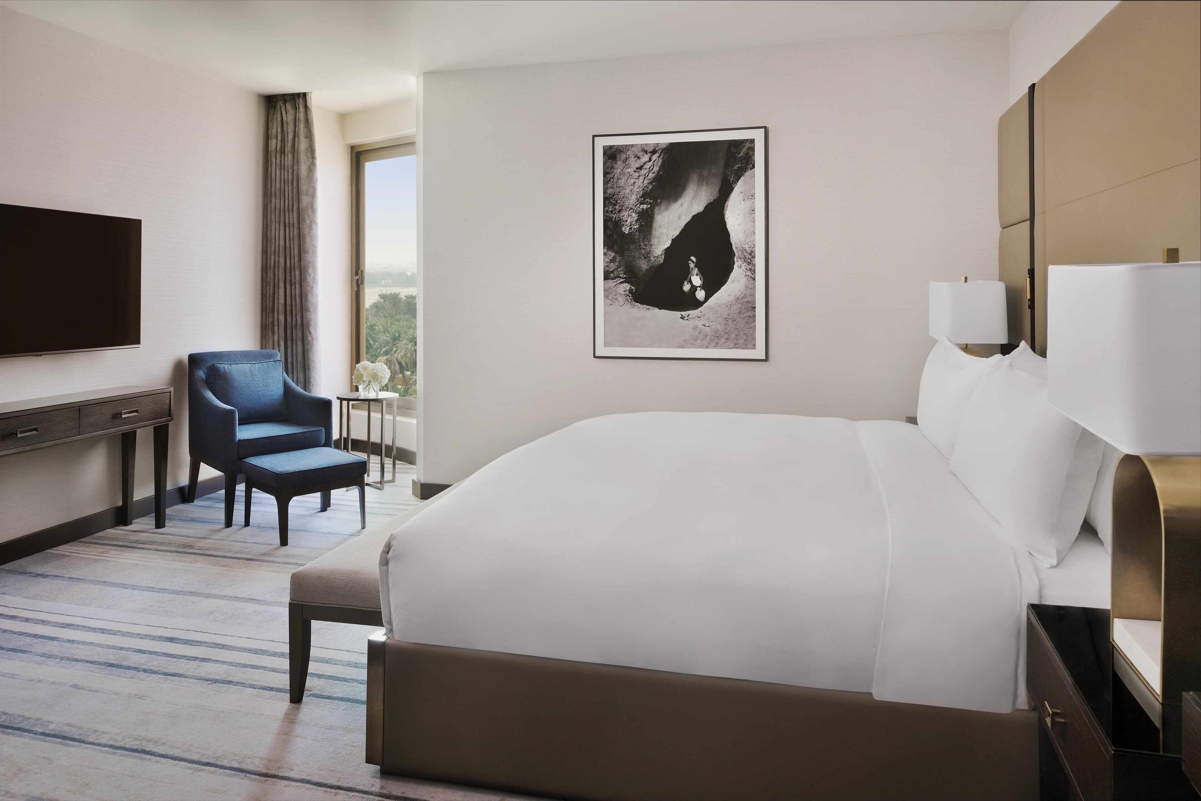 Una habitación de hotel moderna con una cama grande, un escritorio, una silla y un televisor.