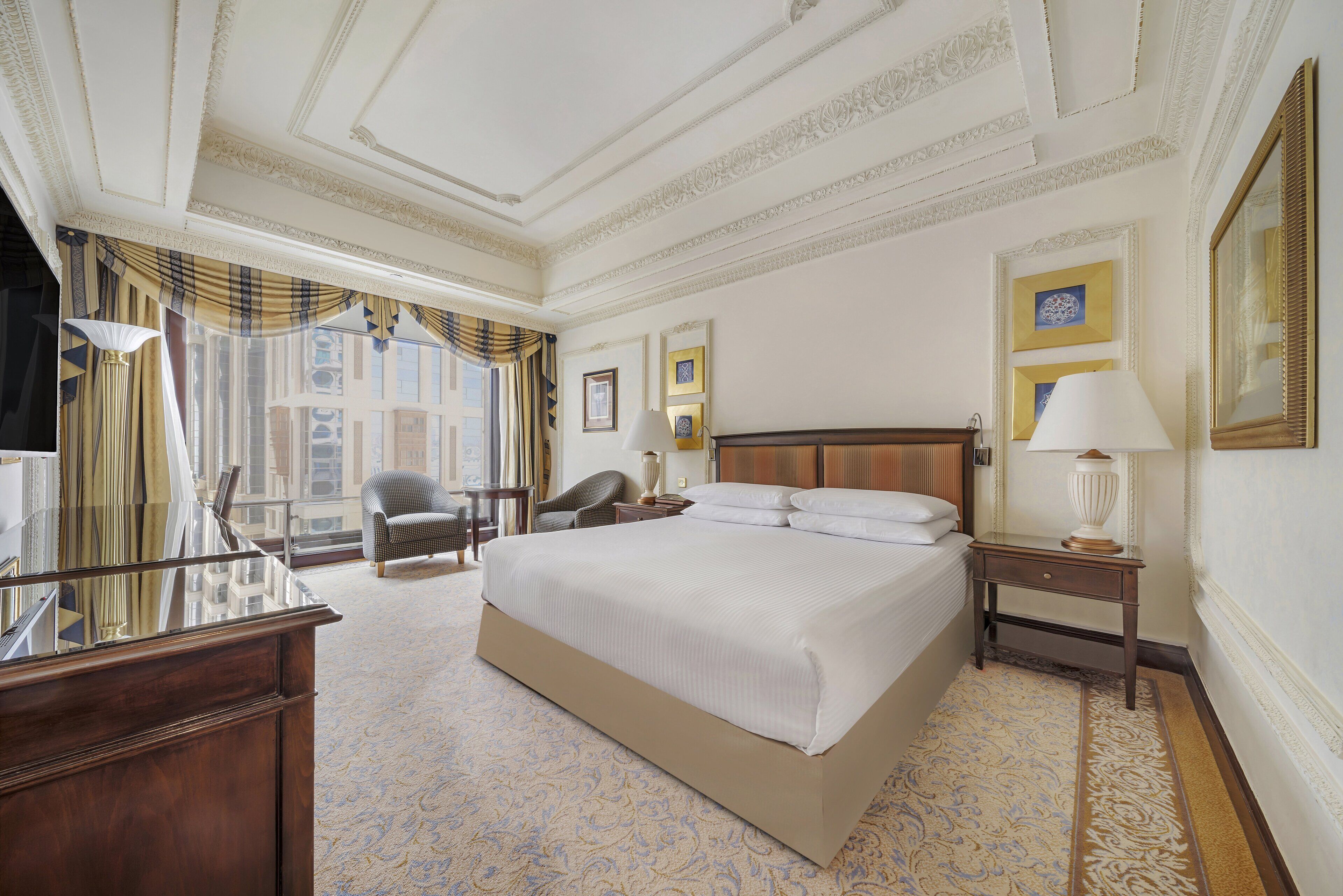 Een hotelkamer met een groot bed, een bureau, een stoel en een nachtkastje.