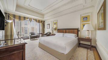 A hotel room with a large bed, a desk, a chair, and a nightstand.