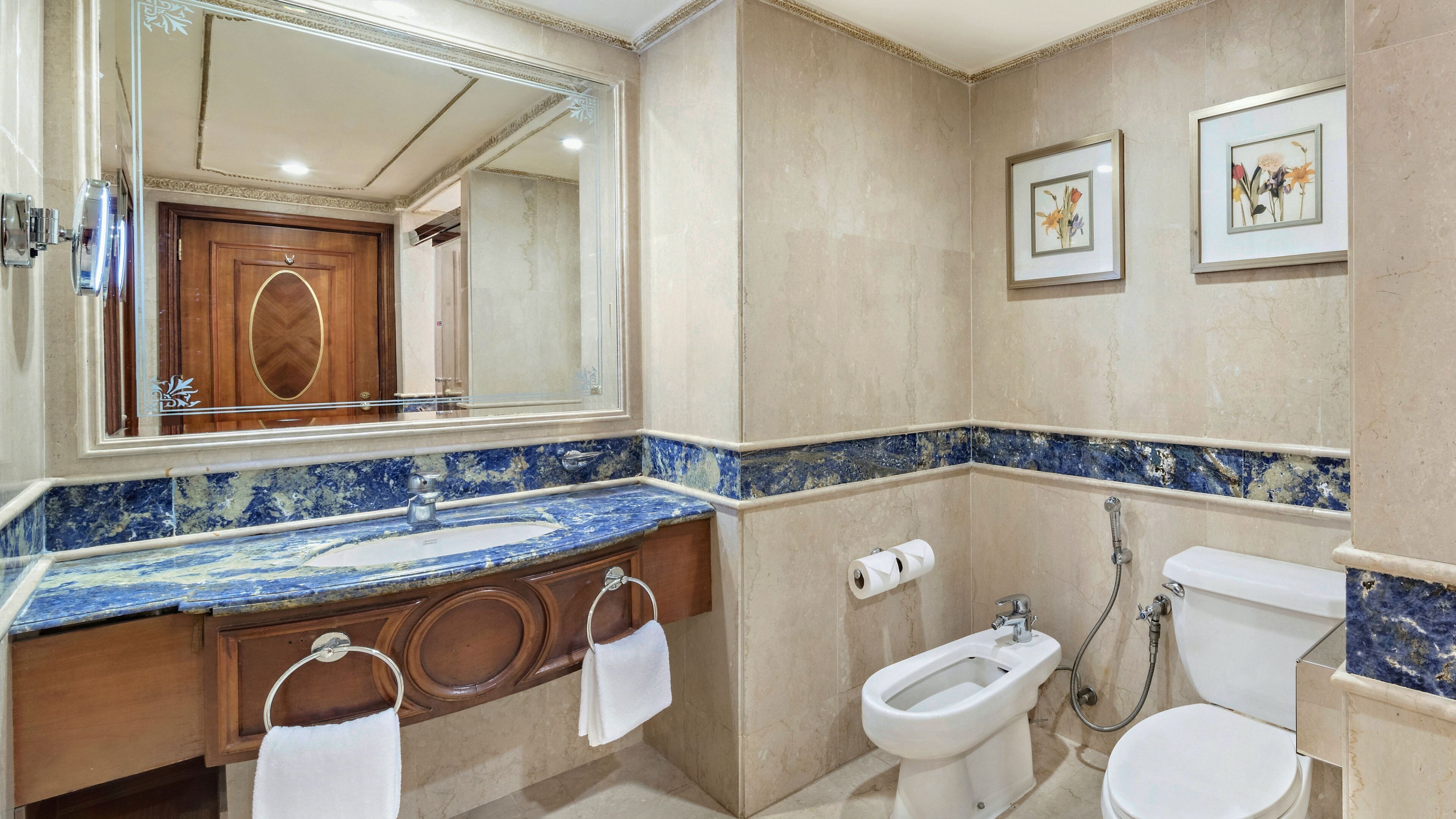 A bathroom with a marble vanity, a bidet, a toilet, and a large mirror.