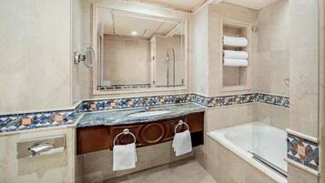 A bathroom with a marble sink, a large mirror, a bathtub, and a towel rack.