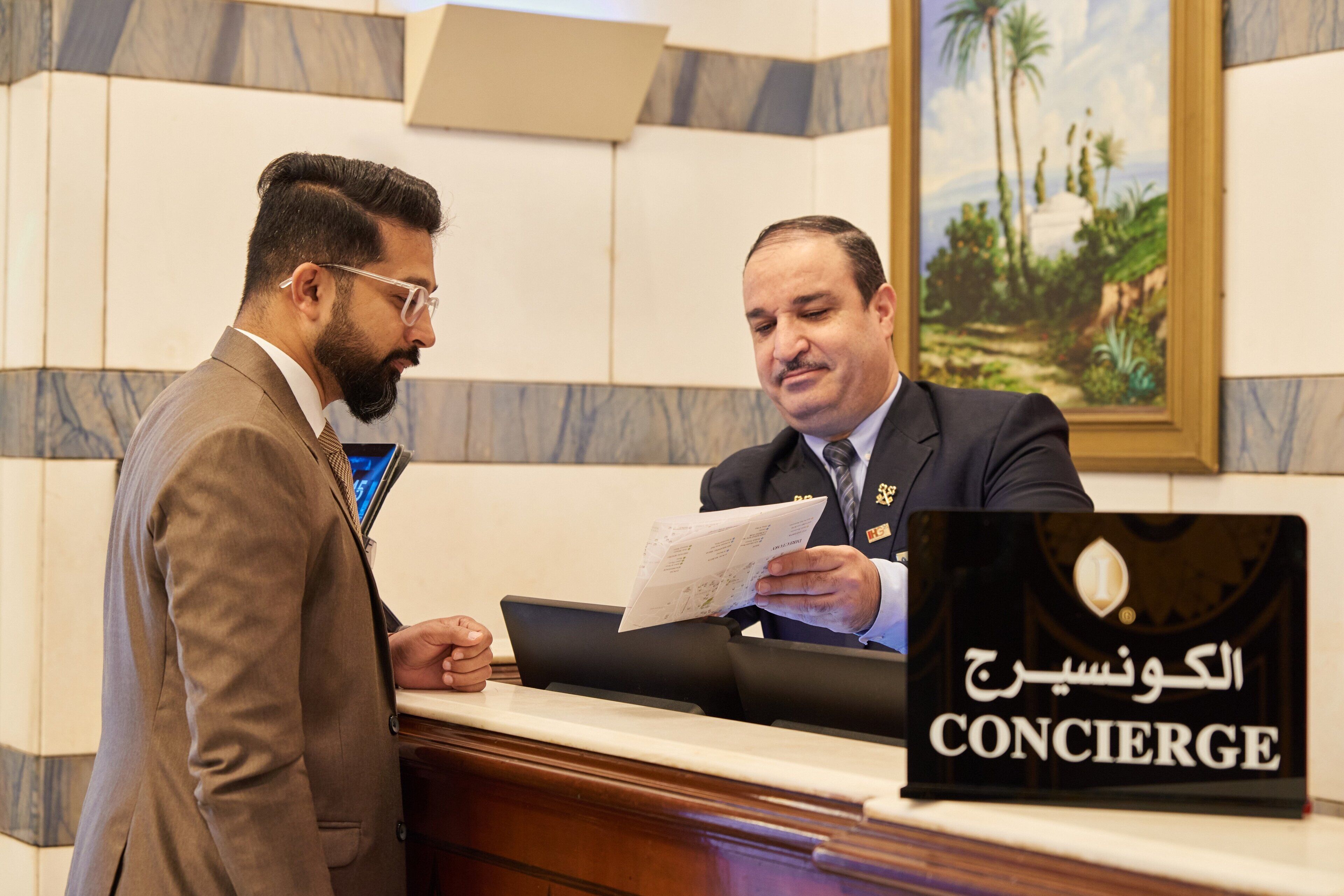 Due uomini dietro una scrivania della reception con un cartello che dice 'Concierge'.
