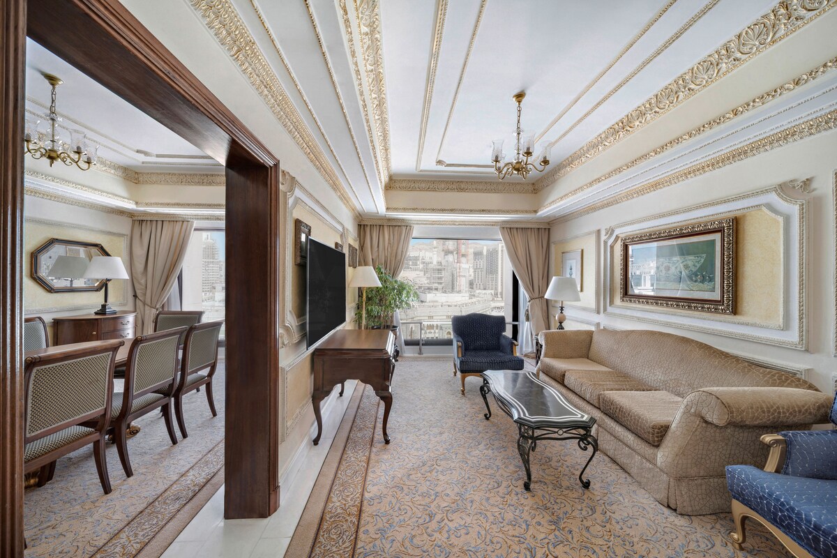 A luxurious room with a dining area, a sofa, a television, and a view of the city.