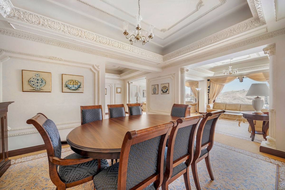 A formal dining room with a round table, six chairs, and a chandelier.