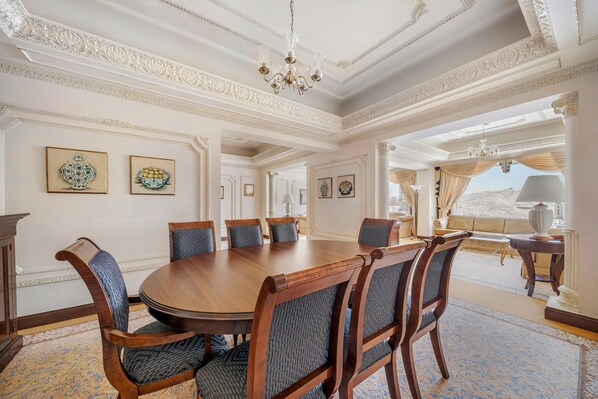 A formal dining room with a round table, six chairs, and a chandelier.