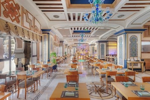 A spacious hotel dining area with multiple tables and chairs, a central bar, and decorative ceiling elements. - Intercontinental Dar Al Tawhid Makkah by IHG (Makkah)