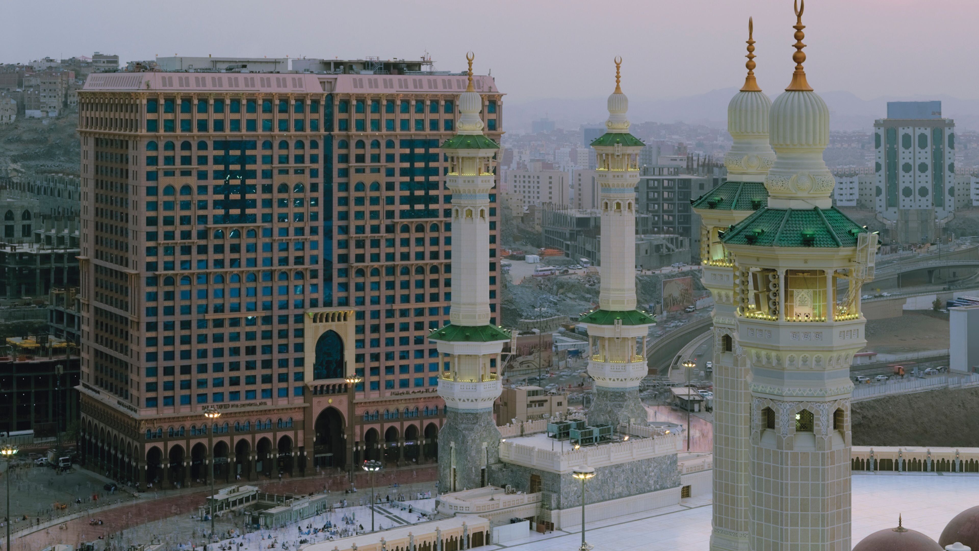A large building with multiple minarets, a courtyard, and surrounding urban landscape.