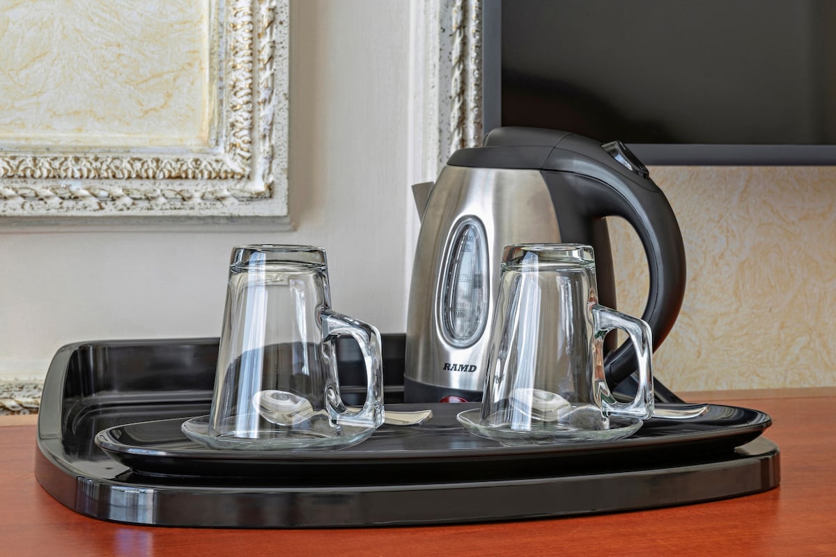 A tray with a kettle and two glass mugs on a wooden table.