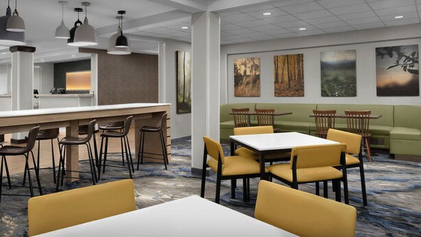 A modern hotel lobby with a bar area, seating arrangements, and artwork on the walls.
