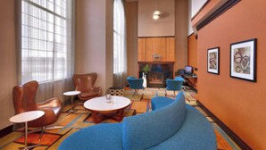 Een hotel lobby met een open haard, een zithoek en kunstwerken aan de muren.