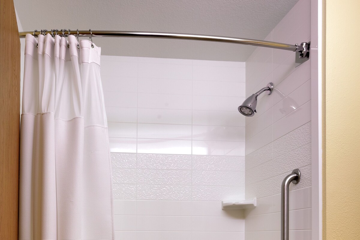 Une salle de bain équipée d’une baignoire, d’un rideau de douche, d’une barre d’appui et d’un porte-serviettes.