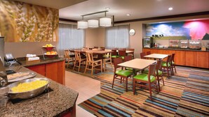 Een restaurantgedeelte in een hotel met een buffet, tafels, stoelen en een grote muurschildering.