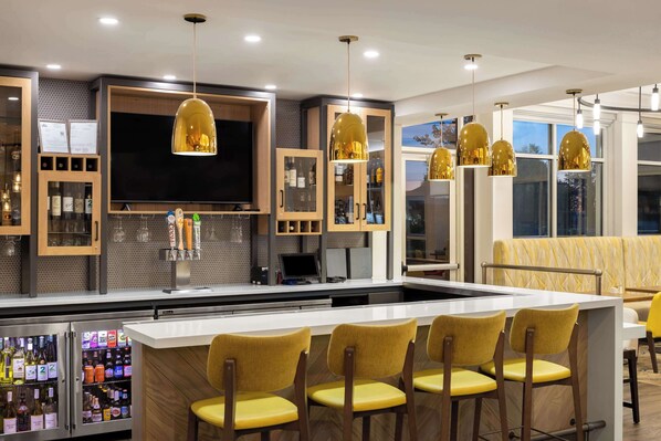 A modern bar area with a central island, bar stools, and pendant lighting.