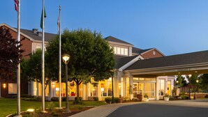 A hotel entrance with a covered driveway, flagpoles, and well-maintained landscaping. - Hilton Garden Inn Spokane Airport (Spokane)