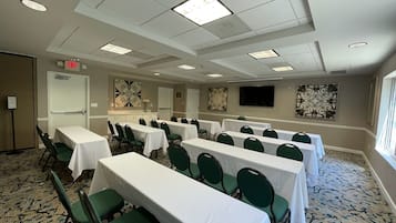 A conference room with multiple tables and chairs, a flat-screen TV, and artwork on the walls.