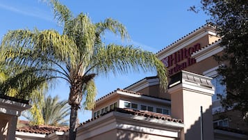 A hotel with a classic architectural style, featuring a prominent sign and a palm tree in the foreground.