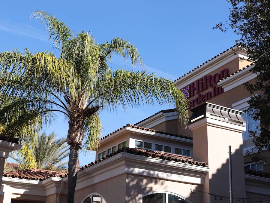A hotel with a classic architectural style, featuring a prominent sign and a palm tree in the foreground.