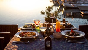 A dining table set with plates of food, drinks, and a lantern. - The Westmarine Waterfront Hotel (La Paz)