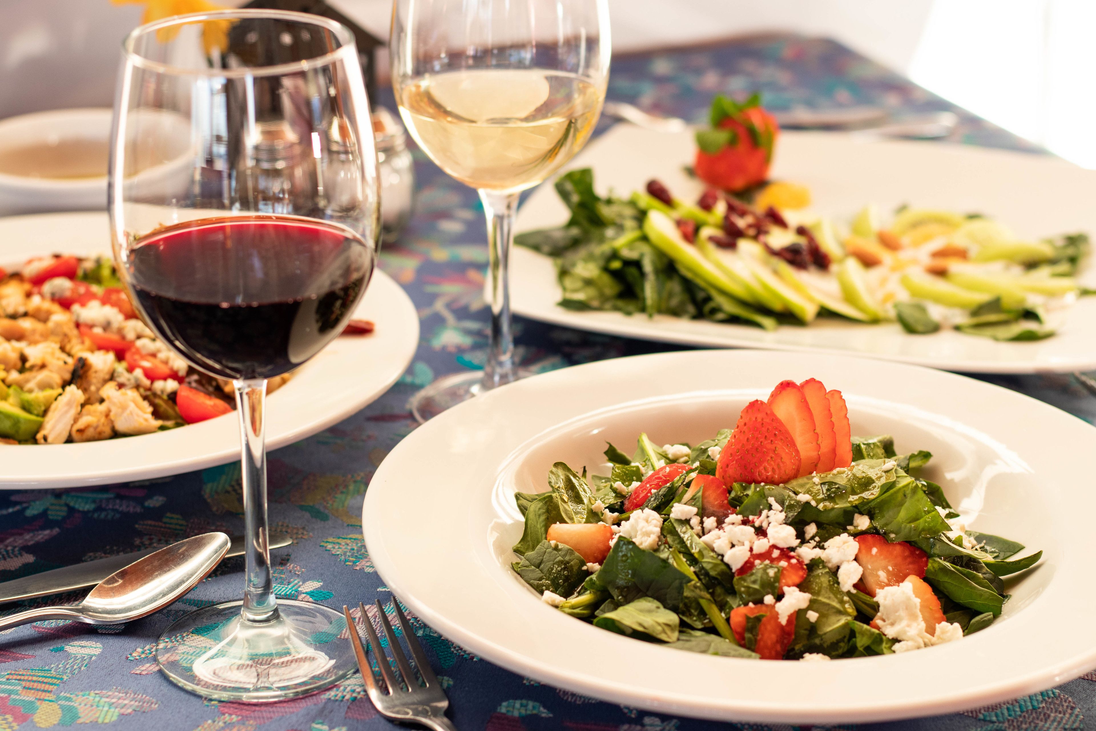 Una mesa con platos de comida, copas de vino y cubiertos.