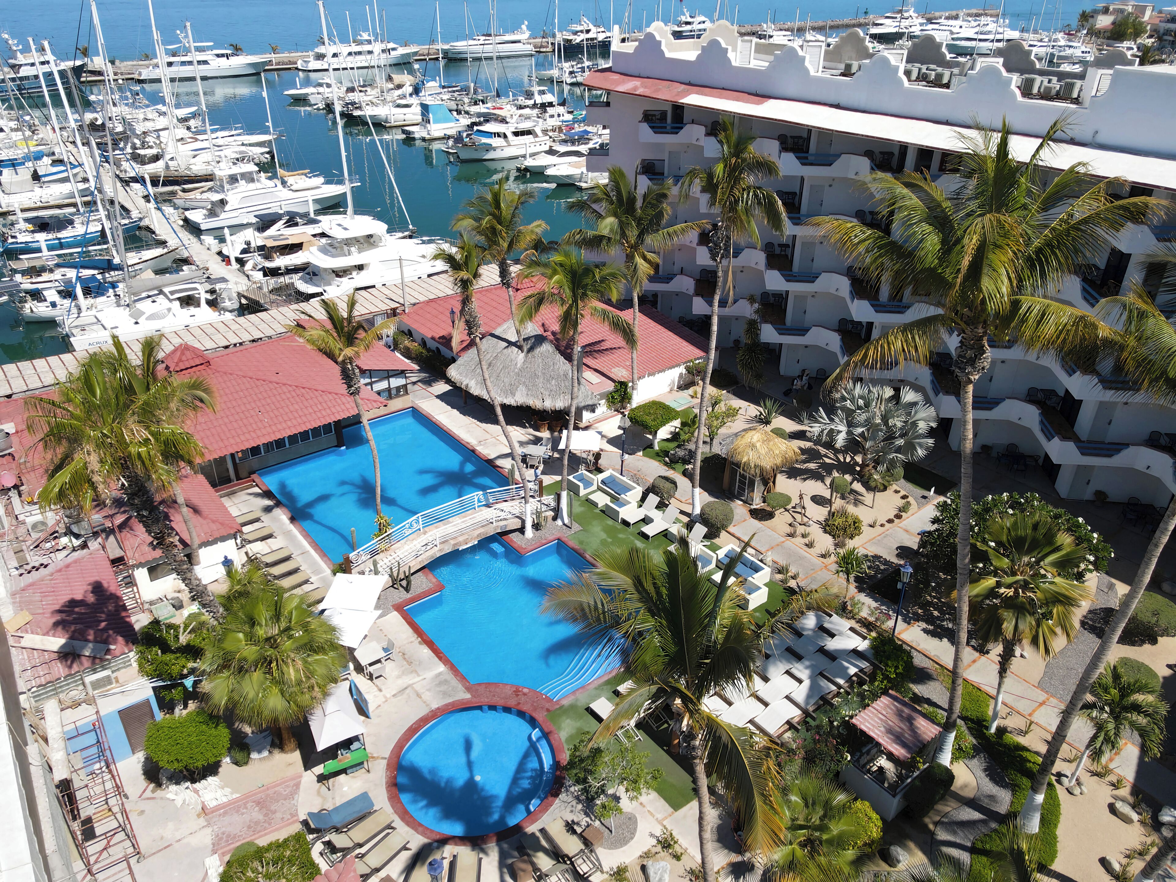Un port de plaisance avec de nombreux bateaux, une piscine et un bâtiment d’hôtel avec des balcons.