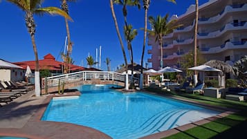 Una piscina al aire libre, sombrillas, sillones reclinables de piscina