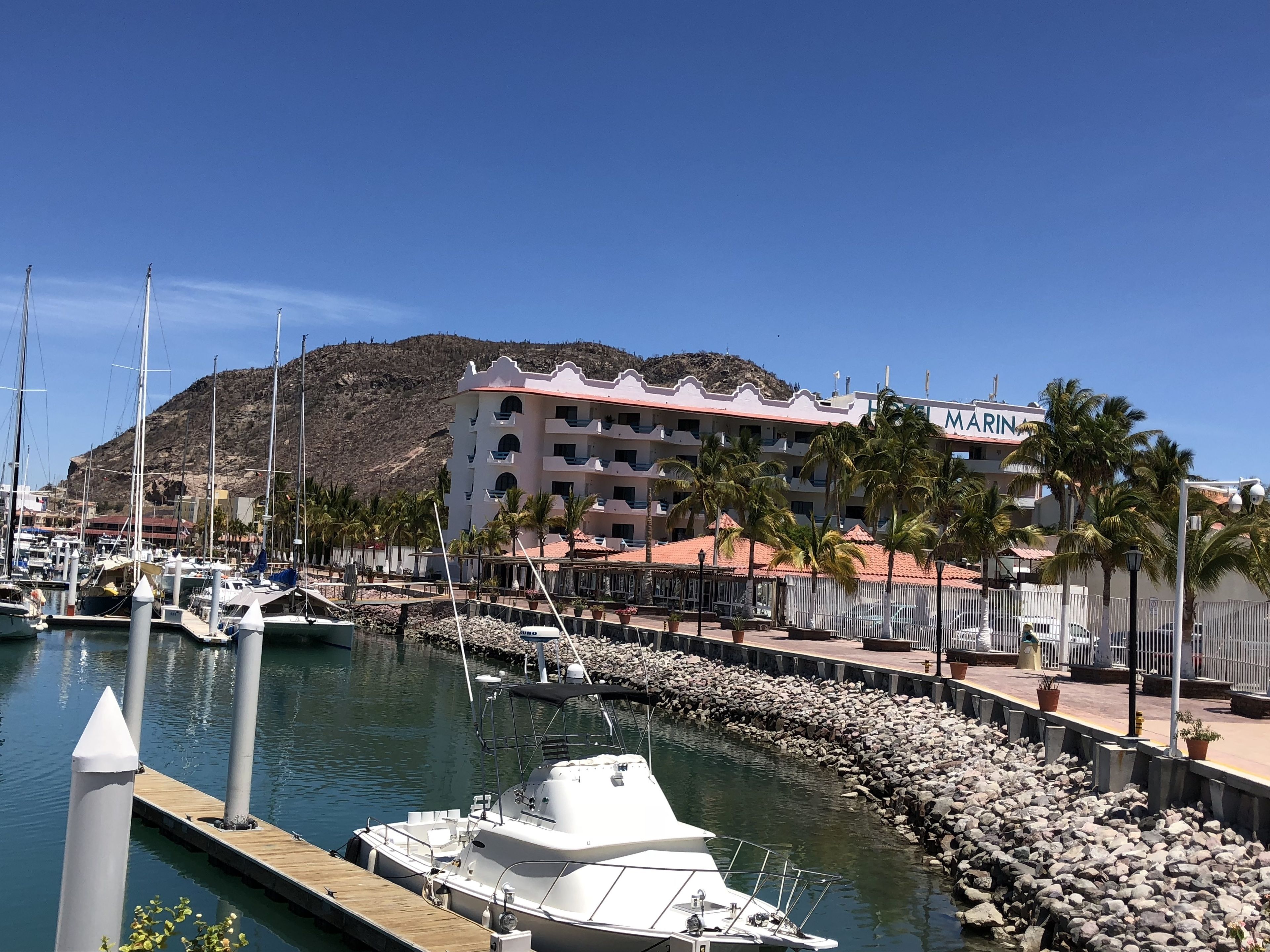 A marina with boats docked, a building labeled "MARINA" in the background, and a rocky shoreline.