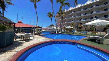 Una piscina al aire libre, sombrillas, sillones reclinables de piscina